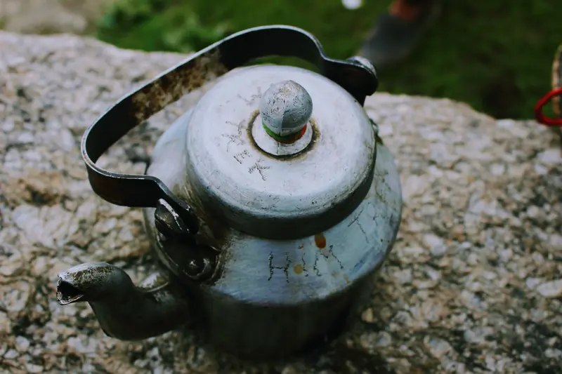 A rustic vintage kettle placed on a stone surface, evokes outdoor charm
