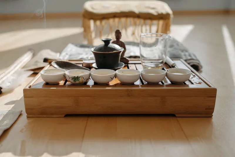 A peaceful tea ceremony setup featuring a Buddha figurine and teacups on a wooden tray
