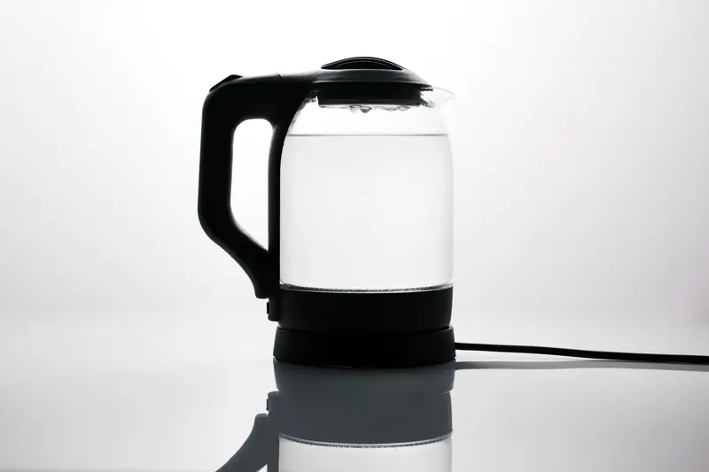 Sleek glass electric kettle with water, reflecting on a glossy surface, ideal for modern kitchens