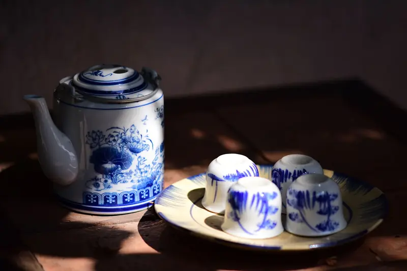 Elegant vintage blue and white teapot with matching cups on a wooden table, creating a cozy classic setting